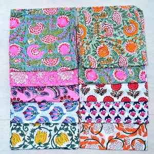 May include: A set of 10 colorful cotton napkins with floral patterns. The napkins are arranged in two rows of five, with each row featuring a different pattern. The patterns include pink, blue, green, orange, and yellow flowers.