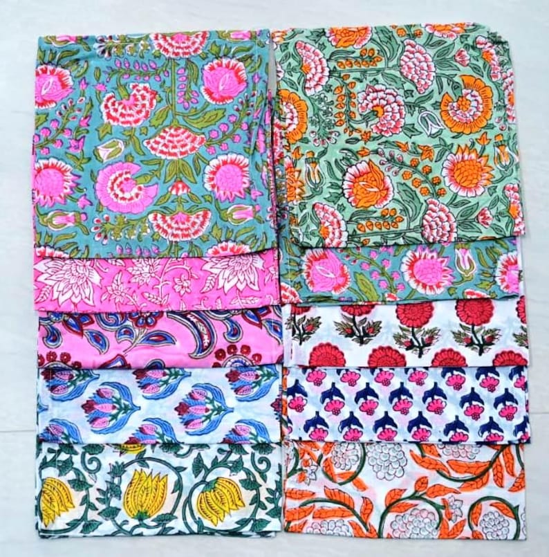 May include: A set of 10 colorful cotton napkins with floral patterns. The napkins are arranged in two rows of five, with each row featuring a different pattern. The patterns include pink, blue, green, orange, and yellow flowers.