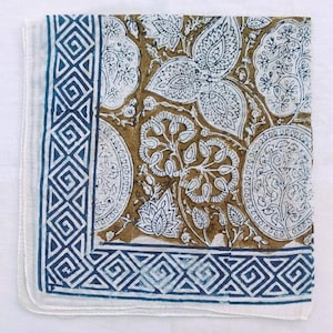 K&ouml;nnte beinhalten: Quadratischer Stoff mit wei&szlig;em und blauem Muster. Der Rand hat ein geometrisches Design in Marineblau. Der Innenraum hat einen braunen Hintergrund mit wei&szlig;en Blumen- und Bl&auml;ttermustern. Es k&ouml;nnte ein Schal oder ein dekoratives Tuch sein.
