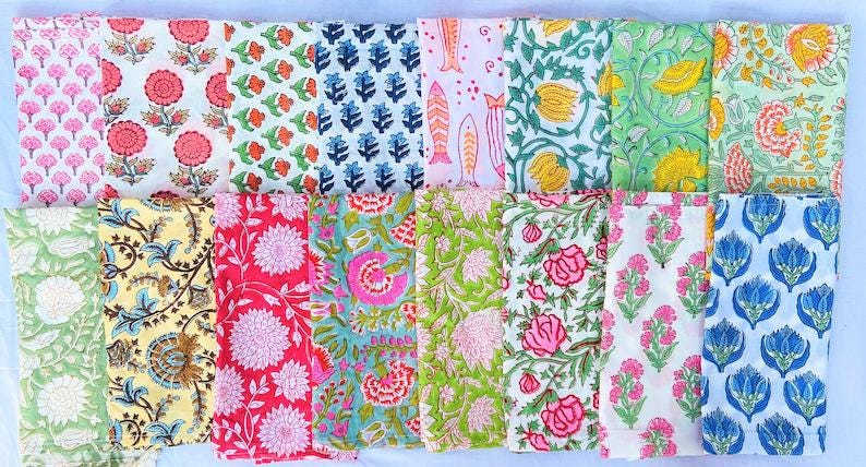 May include: A set of 16 cotton napkins with various floral and geometric patterns in shades of pink, blue, green, yellow, and white.
