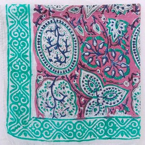 K&ouml;nnte beinhalten: Quadratischer, rosa Textilstoff mit detailliertem Blumenmuster in Wei&szlig;, T&uuml;rkis und Marineblau. Das Design umfasst ovale Formen, Bl&auml;tter und einen t&uuml;rkisfarbenen Rand mit einem komplizierten geometrischen Muster. Der Stoff hat einen wei&szlig;en Rand.