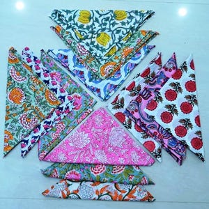 May include: A set of 10 colorful cotton napkins with floral patterns. The napkins are folded into triangles and arranged in a star shape. The napkins are in shades of pink, green, blue, and white.