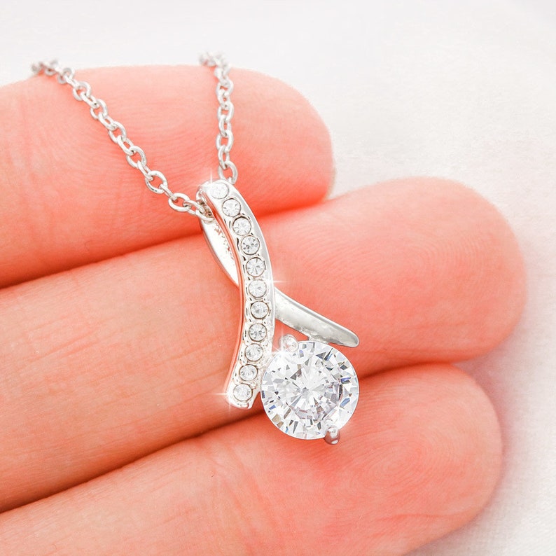 May include: A silver necklace with a large, clear, round gemstone pendant. The pendant is set in a silver setting with smaller clear gemstones around the edge. The necklace is on a delicate silver chain.