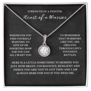 May include: A silver necklace with a clear crystal pendant in a black gift box. The box has an inspirational message that reads "Strength of a fighter, Heart of a warrior. Whenever you find yourself wanting to give up or doubting how far you can go, I want you to remember that warriors, like you, are created through life's toughest battles. Here is a little something to remind you just how brave, courageous, resilient and fierce you are! You've got this! And I am always here for you if you need me."