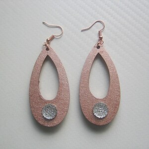 Puede incluir: Un par de pendientes en forma de lágrima, de color oro rosa. Tienen una superficie texturizada y un pequeño adorno redondo plateado. Los ganchos son de color oro rosa. Cada pendiente mide aproximadamente 6 cm de largo.