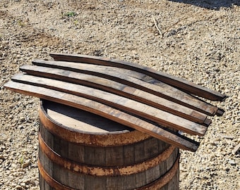 May include: Stacked wooden barrel staves, ready to be assembled into a barrel. The staves are arranged on top of a wooden barrel.