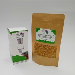 May include: A brown paper bag with a clear window showing yellow bee pollen. The bag has a label that says "Sticky Tongue USA" and "Premium Bee Pollen". The bag is next to a white box with a green label that says "Sticky Tongue USA" and "Premium Pollen Grinder".