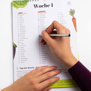 May include: A checklist for fruits and vegetables with a hand checking off items on the list. The list is divided into two sections: "Obst" (German for fruit) and "Gem&uuml;se" (German for vegetables). The list includes a variety of fruits and vegetables, such as apples, bananas, carrots, and spinach. The checklist is titled "Woche 1" (German for week 1).