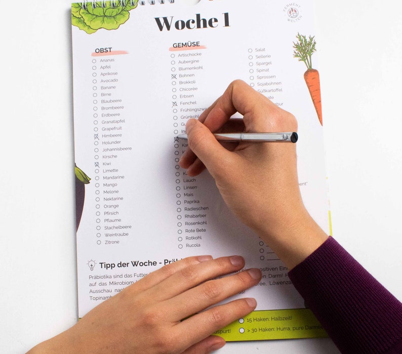 May include: A checklist for fruits and vegetables with a hand checking off items on the list. The list is divided into two sections: "Obst" (German for fruit) and "Gem&uuml;se" (German for vegetables). The list includes a variety of fruits and vegetables, such as apples, bananas, carrots, and spinach. The checklist is titled "Woche 1" (German for week 1).