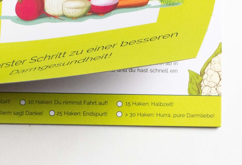 May include: A yellow card with a checklist for gut health. The checklist includes the following milestones: Start, 10 hooks: You're gaining momentum, 15 hooks: Halftime, 25 hooks: You're in the final stretch, and 30 hooks: You've reached your goal. The card is decorated with illustrations of vegetables.