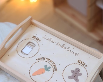May include: A wooden tray with a white background and the text "Lieber Nikolaus!"  The tray has three circles with images of a glass of milk, a carrot, and a gingerbread man. The text "Guten Appetit! Simon" is at the bottom of the tray.
