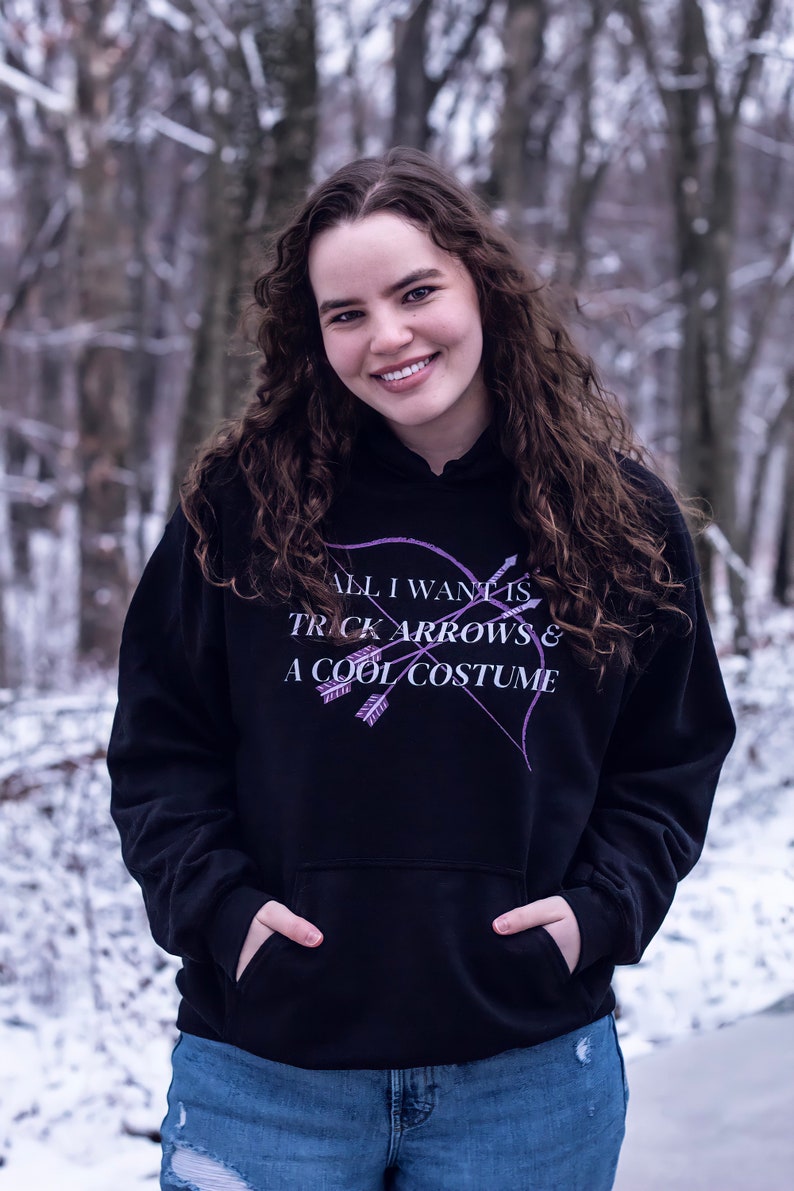 Marvel Hawkeye tv show hoodie inspired by Kate Bishop's quotes to Clint Barton, “All I Want Is Trick Arrows & A Cool Costume," with art of bow and arrows. Perfect merchandise or gift for a Marvel fan!