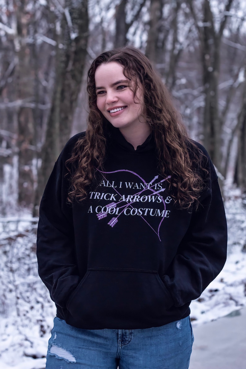 Marvel Hawkeye tv show hoodie inspired by Kate Bishop's quotes to Clint Barton, “All I Want Is Trick Arrows & A Cool Costume," with art of bow and arrows. Perfect merchandise or gift for a Marvel fan!