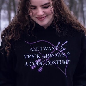 Marvel Hawkeye tv show hoodie inspired by Kate Bishop's quotes to Clint Barton, “All I Want Is Trick Arrows & A Cool Costume," with art of bow and arrows. Perfect merchandise or gift for a Marvel fan!