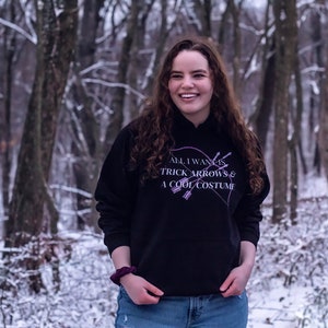 Marvel Hawkeye tv show hoodie inspired by Kate Bishop's quotes to Clint Barton, “All I Want Is Trick Arrows & A Cool Costume," with art of bow and arrows. Perfect merchandise or gift for a Marvel fan!