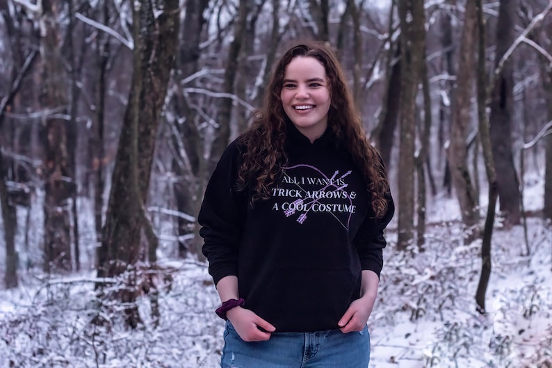 Marvel Hawkeye tv show hoodie inspired by Kate Bishop's quotes to Clint Barton, “All I Want Is Trick Arrows & A Cool Costume," with art of bow and arrows. Perfect merchandise or gift for a Marvel fan!
