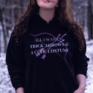 Marvel Hawkeye tv show hoodie inspired by Kate Bishop's quotes to Clint Barton, “All I Want Is Trick Arrows & A Cool Costume," with art of bow and arrows. Perfect merchandise or gift for a Marvel fan!