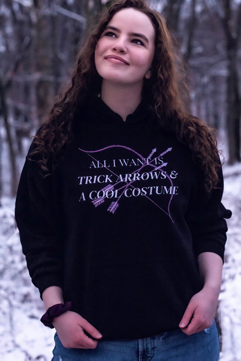Marvel Hawkeye tv show hoodie inspired by Kate Bishop's quotes to Clint Barton, “All I Want Is Trick Arrows & A Cool Costume," with art of bow and arrows. Perfect merchandise or gift for a Marvel fan!