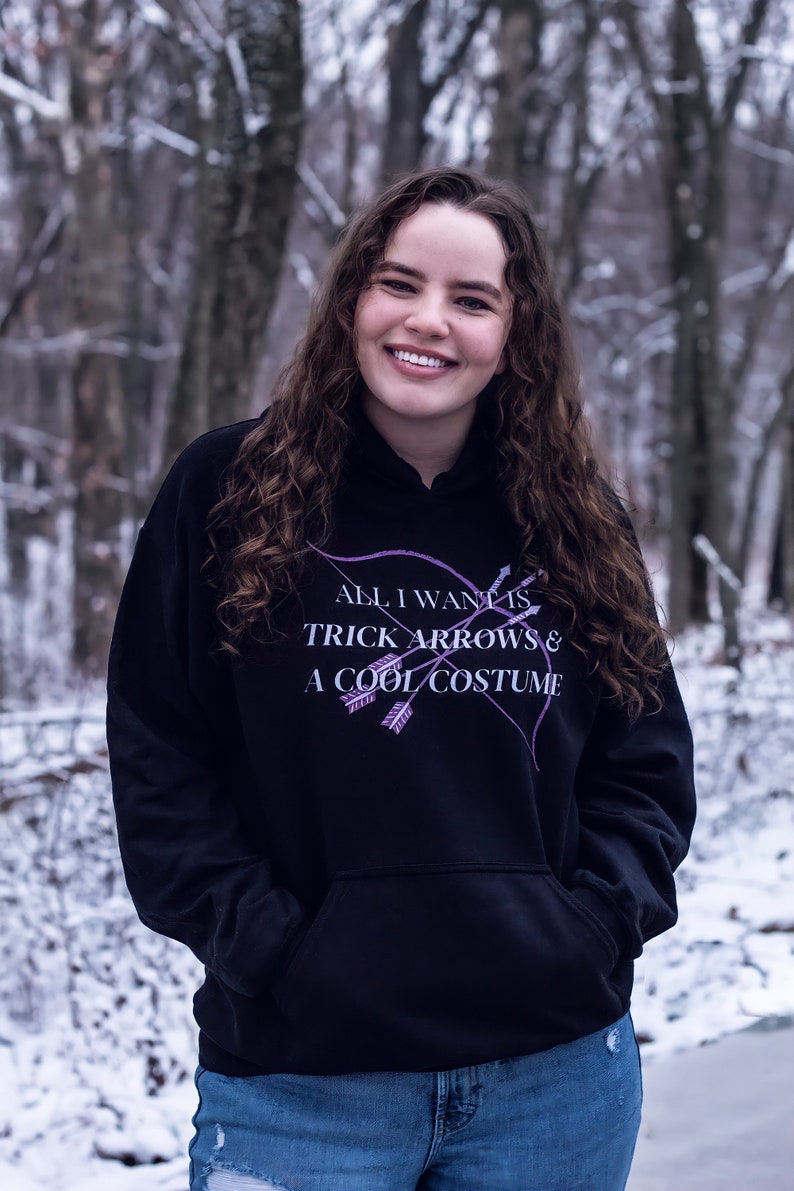 Marvel Hawkeye tv show hoodie inspired by Kate Bishop's quotes to Clint Barton, “All I Want Is Trick Arrows & A Cool Costume," with art of bow and arrows. Perfect merchandise or gift for a Marvel fan!