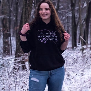 Marvel Hawkeye tv show hoodie inspired by Kate Bishop's quotes to Clint Barton, “All I Want Is Trick Arrows & A Cool Costume," with art of bow and arrows. Perfect merchandise or gift for a Marvel fan!