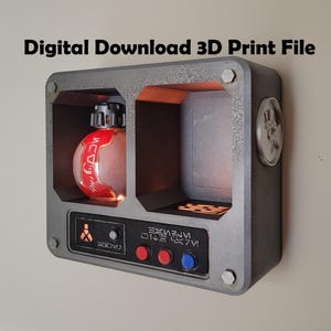 Puede incluir: Una vitrina rectangular gris impresa en 3D con dos compartimentos. Uno contiene una botella roja y blanca. La caja tiene botones rojos y azules, y el texto "Digital Download 3D Print File" está en la parte superior.