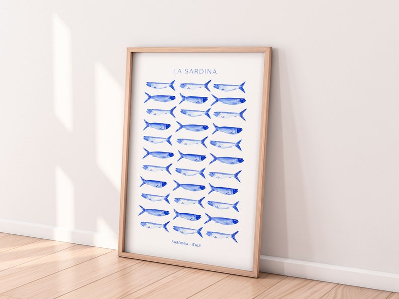 Puede incluir: Una impresi&oacute;n enmarcada con fondo blanco e ilustraciones de peces en acuarela azul. El texto "LA SARDINA" est&aacute; en la parte superior de la impresi&oacute;n y "SARDINIA, ITALY" en la parte inferior.