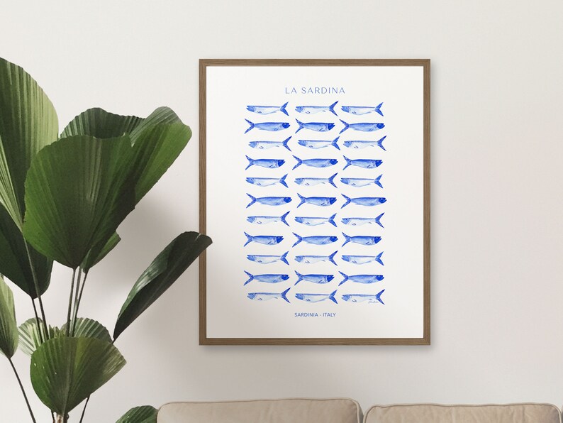 Puede incluir: Una impresi&oacute;n enmarcada con fondo blanco e ilustraciones de sardinas en acuarela azul. El texto "LA SARDINA" est&aacute; en la parte superior de la impresi&oacute;n y "SARDINIA, ITALY" en la parte inferior.