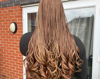 May include: Long, brown and blonde micro braids with a curly style. The braids are styled in a way that creates a wavy look.