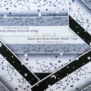 May include: Black and gray washi tape with a repeating pattern of branches, leaves, stars, and a crescent moon. The tape is labeled "Black and Gray Dream Washi Tape" and "Kiki's Stationery Service".