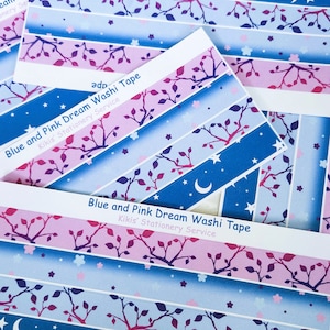 May include: A set of five blue and pink washi tapes with a moon and stars design. The tapes feature a repeating pattern of branches with leaves and small flowers. The text on the tapes reads "Blue and Pink Dream Washi Tape" and "Kikis' Stationery Service".