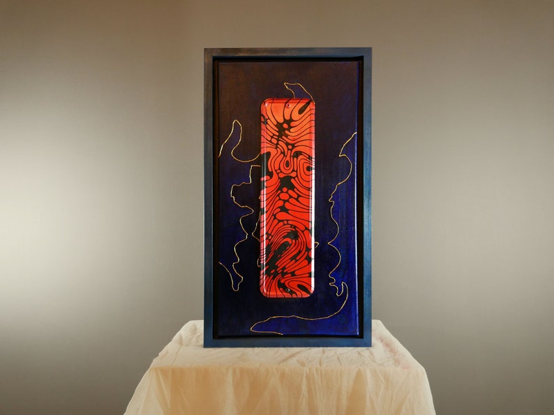 K&ouml;nnte beinhalten: Ein rechteckiges gerahmtes Kunstwerk mit einem tiefblauen Hintergrund und d&uuml;nnen goldenen Linienakzenten. In der Mitte des Rahmens befindet sich eine vertikale, gl&auml;nzend rote Platte mit einem schwarzen, flie&szlig;enden, organischen Muster.