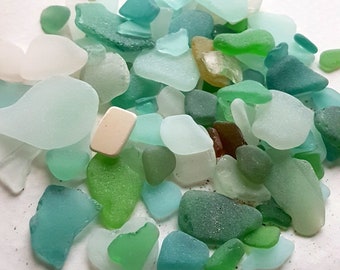 May include: A collection of sea glass in various shades of green, blue, and white. The sea glass is smooth and polished, with a variety of shapes and sizes.