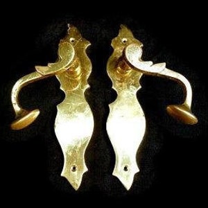 K&ouml;nnte beinhalten: Zwei verzierte goldene T&uuml;rklinken mit aufwendigen Designs. Die Griffe haben eine gebogene Form und einen kleinen Knopf am Ende.