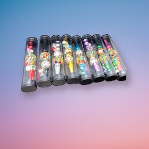 May include: Ten colorful jeweled smoking pipes in clear plastic tubes. Each pipe has a different color and is decorated with colorful jewels.