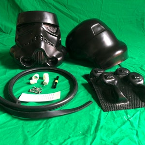 May include: A black plastic Star Wars Stormtrooper helmet kit with two helmet pieces, a black rubber seal, a black marker, white plastic connectors, silver screws, and black plastic pieces.