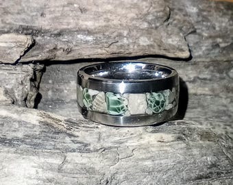 Op de afbeelding: Een zilveren ring met een band van groene en witte stenen die in een zilveren band zijn gezet.