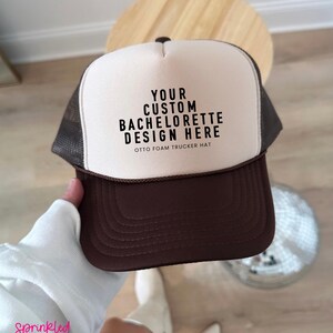 May include: A brown and white trucker hat with the text "YOUR CUSTOM BACHELORETTE DESIGN HERE" printed on the front. The hat is made of foam and has a mesh back. The hat is a front split brown Otto Foam Trucker Hat.