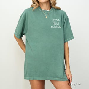 May include: Light green t-shirt with the text "Kelsey's Bachelorette" and a graphic of four shamrocks.