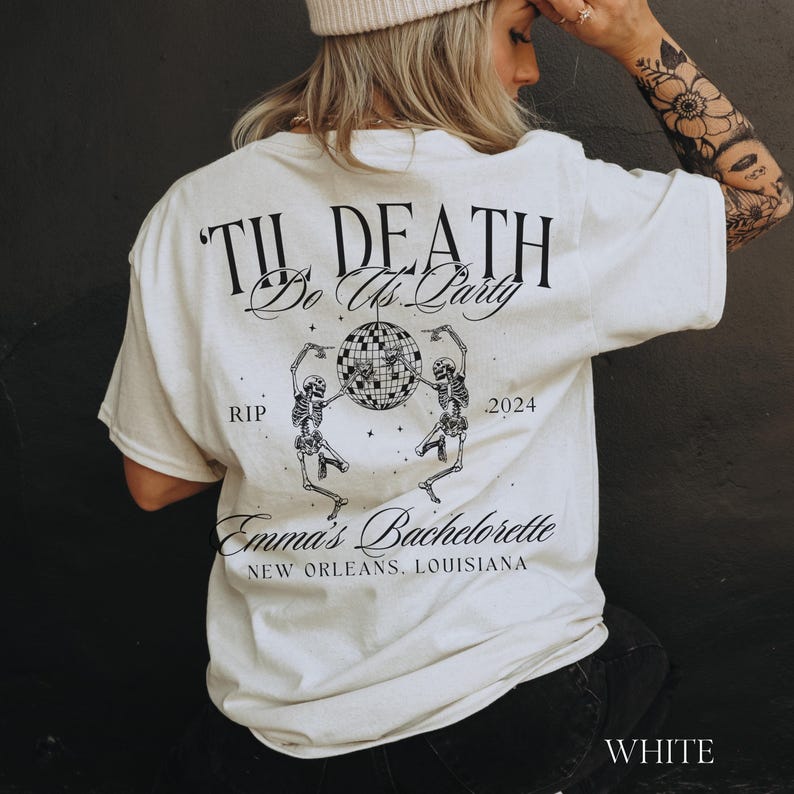 May include: White t-shirt with black text that reads "Til Death Do Us Party" with two skeletons dancing around a disco ball. The text "RIP" and "2024" are on either side of the disco ball. Below the skeletons is the text "Emma's Bachelorette New Orleans, Louisiana".