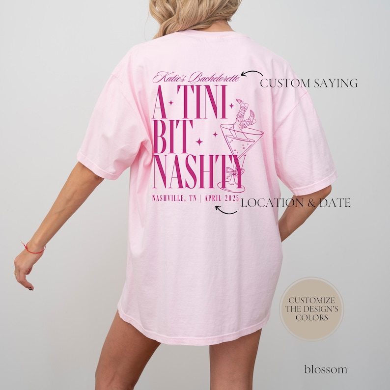 May include: Pink t-shirt with a pink graphic design that says "A-Tini Bit+ Nashty" with a martini glass and a woman's legs in cowboy boots hanging out of the glass. The text "Katie's Bachelorette" is at the top of the design. The text "Nashville, TN | April 2025" is at the bottom of the design.