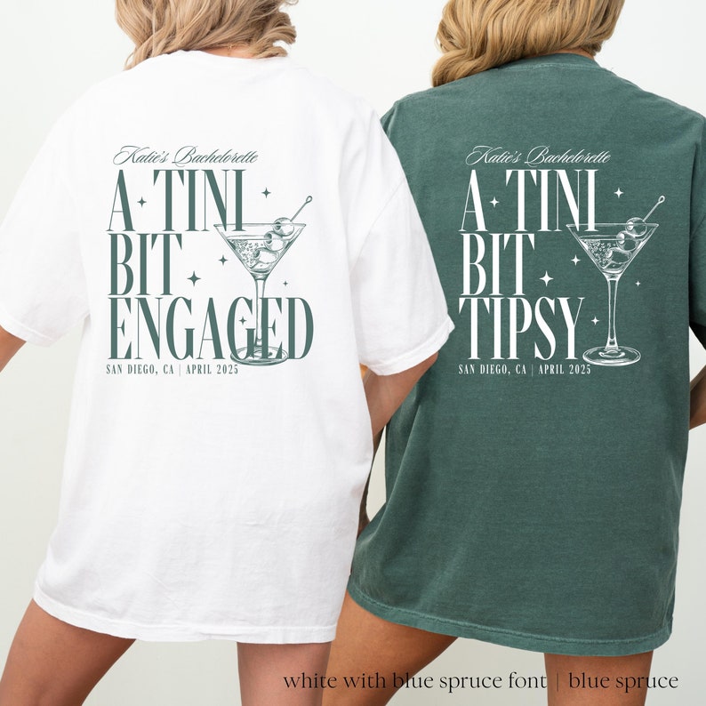 May include: Two white t-shirts with a green design. The text on the shirts reads "Katie's Bachelorette A-TINI BIT ENGAGED" and "Katie's Bachelorette A-TINI BIT TIPSY". The shirts have a martini glass graphic with olives.