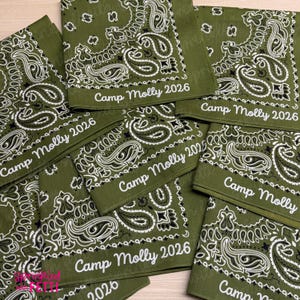 May include: A collection of olive green bandanas featuring a white paisley pattern and the text Camp Molly 2026 printed in a script font. Each square fabric accessory displays the same repeating intricate design and personalized lettering.