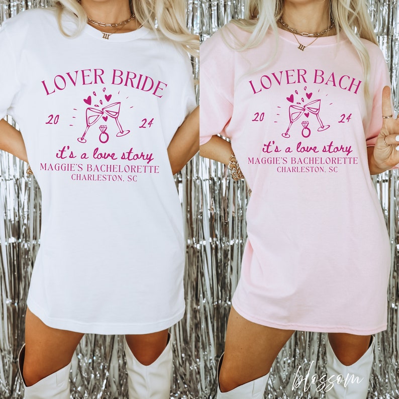 May include: Two white t-shirts with pink text. The text on the left shirt reads "Lover Bride 20 - 24 it's a love story Maggie's Bachelorette Charleston, SC". The text on the right shirt reads "Lover Bach 20 - 24 it's a love story Maggie's Bachelorette Charleston, SC".