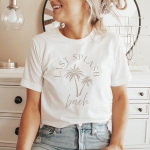 Puede incluir: Camiseta blanca con un gr&aacute;fico de palmeras y el texto "Last Splash Bach".