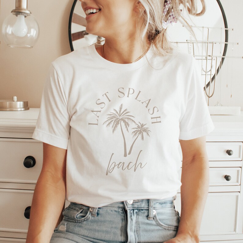 Puede incluir: Camiseta blanca con un gr&aacute;fico de palmeras y el texto "Last Splash Bach".