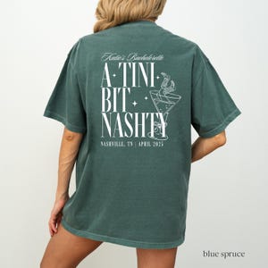 May include: A green t-shirt with white text that reads "Katie's Bachelorette A-TINI BIT NASHTY NASHVILLE, TN | APRIL 2025". The shirt features a graphic of a martini glass with a straw.