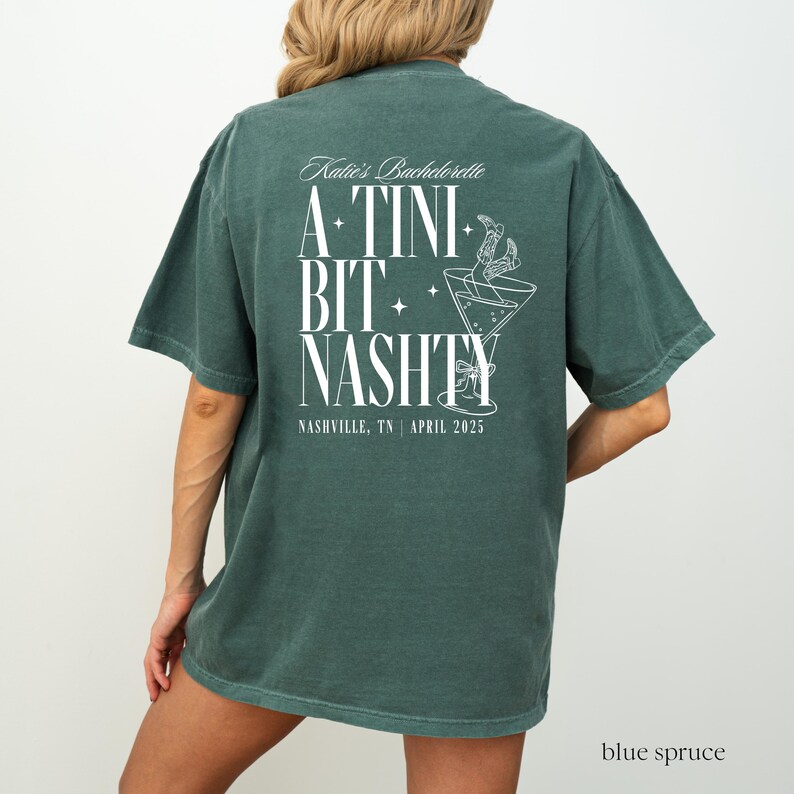 May include: A green t-shirt with white text that reads "Katie's Bachelorette A-TINI BIT NASHTY NASHVILLE, TN | APRIL 2025". The shirt features a graphic of a martini glass with a straw.