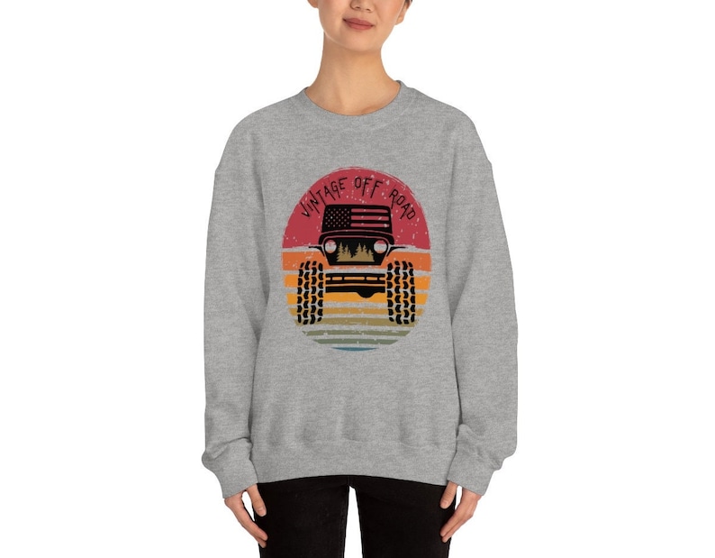 Puede incluir: Sudadera gris con un gr&aacute;fico de un jeep vintage todoterreno en un c&iacute;rculo con un fondo de puesta de sol. El texto "Vintage Off Road" est&aacute; escrito alrededor del c&iacute;rculo.
