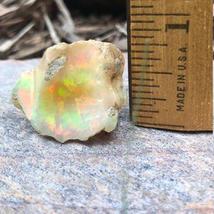 Puede incluir: Un &oacute;palo blanco rugoso con destellos iridiscentes verdes, naranjas y rojos. El &oacute;palo tiene un di&aacute;metro de aproximadamente 2,5 cm y est&aacute; al lado de una regla para la escala. "MADE IN U.S.A." est&aacute; impreso en la regla.