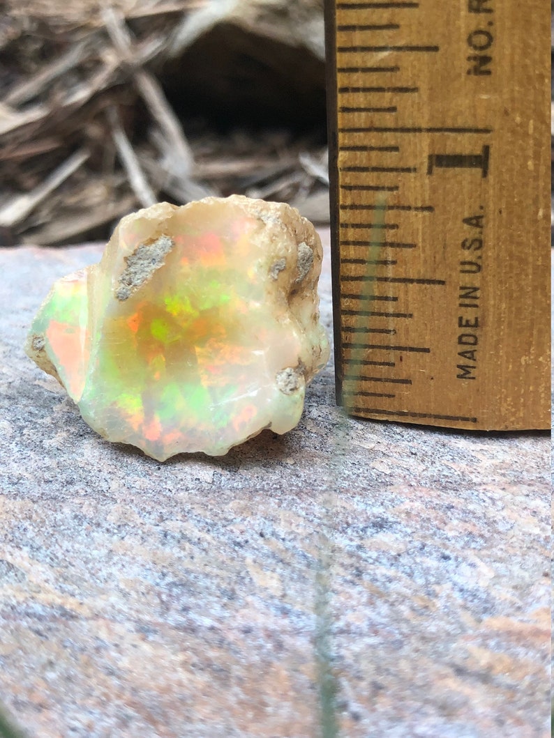 Puede incluir: Un &oacute;palo blanco rugoso con destellos iridiscentes verdes, naranjas y rojos. El &oacute;palo tiene un di&aacute;metro de aproximadamente 2,5 cm y est&aacute; al lado de una regla para la escala. "MADE IN U.S.A." est&aacute; impreso en la regla.